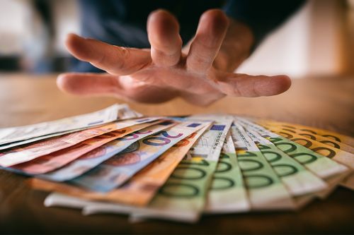 Foto: Hand über Geldscheinen